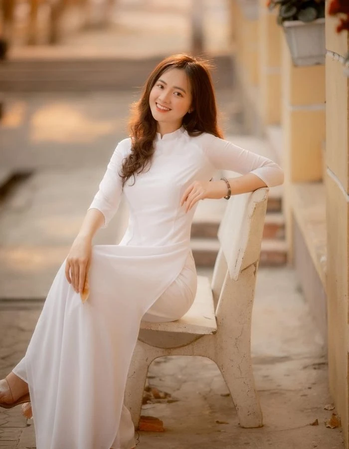 Áo dài trắng học sinh tạo dáng trên ghế đá trường học